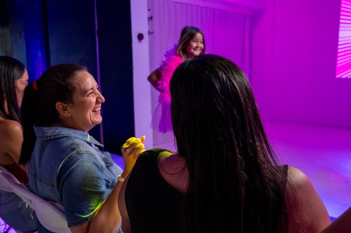 A parent laughing while watching her daughter walk the runway