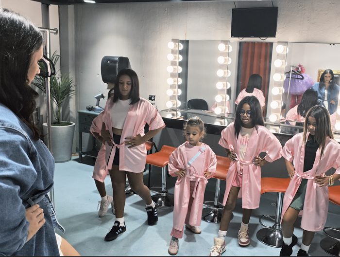 Girls in pink robes getting ready together at the vanity mirrors before the show
