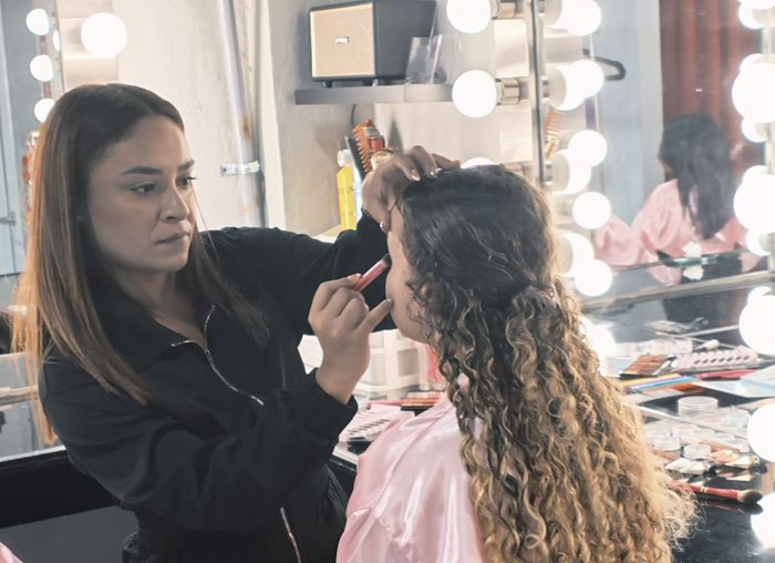 Girls in pink robes seated at the makeup station mirrors