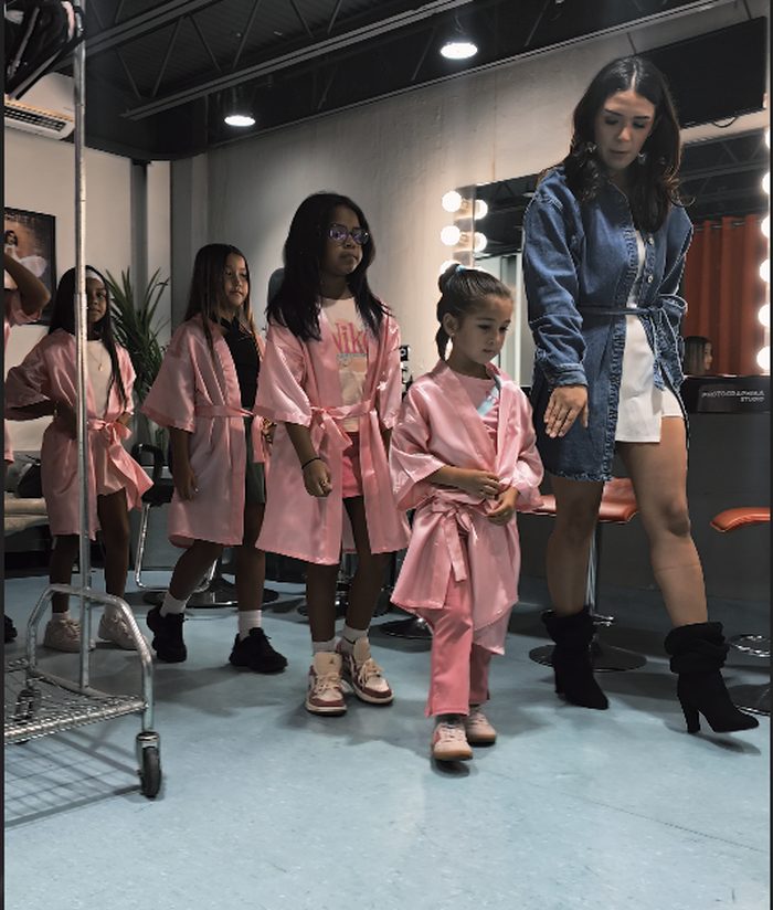 Girls in pink robes lined up with their coach during runway class